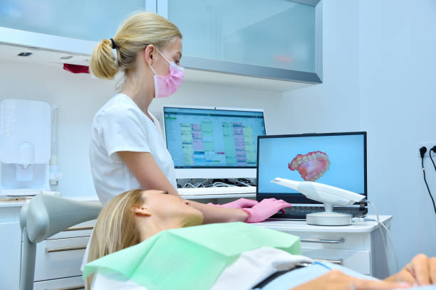 Dentist and patient are watching result of a 3D scan on a laptop monitor stock photo