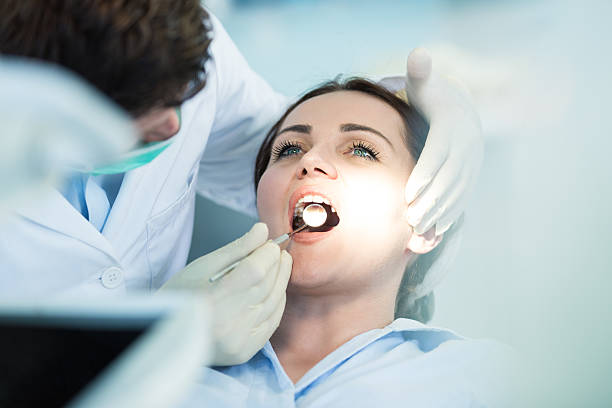 Dentist examining Patient teeth with a Mouth Mirror. stock photo