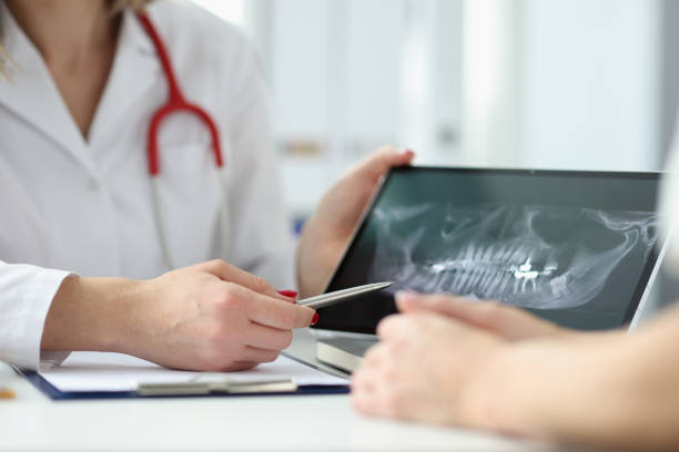 Dentist showing patient tablet with x-ray of teeth in clinic closeup stock photo