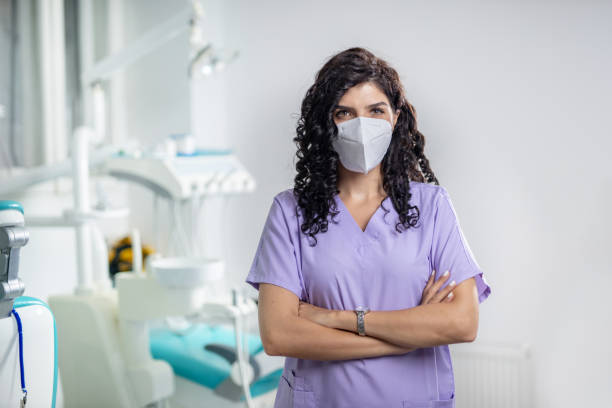 Dentist standing in office, arms crossed stock photo