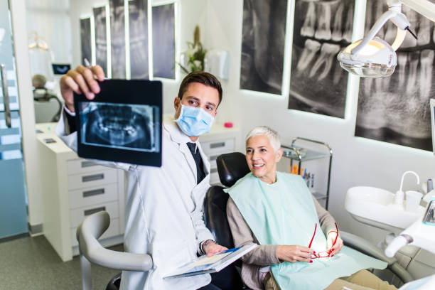 Dentist work Handsome male dentist checking x-ray image or scan while beautiful senior woman receiving a dental treatment. x ray image photos stock pictures, royalty-free photos & images