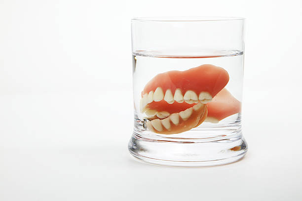 Dentures in a glass of water stock photo
