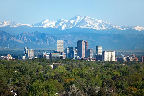 Denver Colorado skyscrapers snowy Longs Peak Rocky Mountains summer Snow covered Longs Peak, part of the Rocky Mountains stands tall in the background with green trees and the Downtown Denver skyscrapers as well as hotels, office buildings and apartment buildings filling the skyline. urban skyline photos stock pictures, royalty-free photos & images