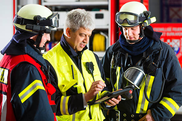 deployment planning on Tablet-Computer Fire brigade - Squad leader gives instructions, he used the Tablet Computer to plan the deployment firefighters stock pictures, royalty-free photos & images