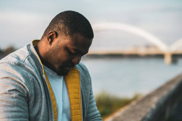 Depressed black man Depressed black man sitting outdoor. depression land feature stock pictures, royalty-free photos & images