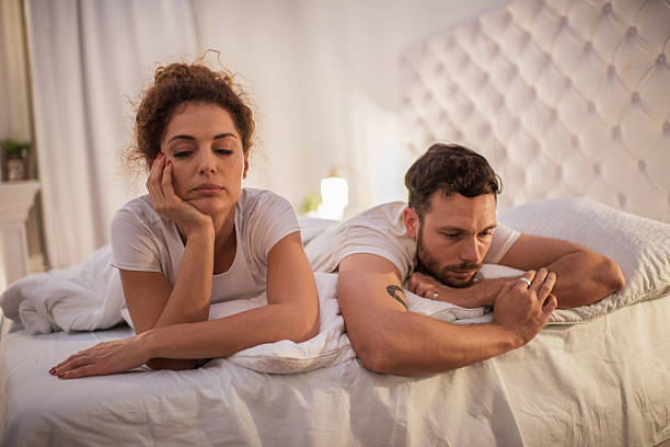 Depressed couple having relationship problems in their bed. stock photo