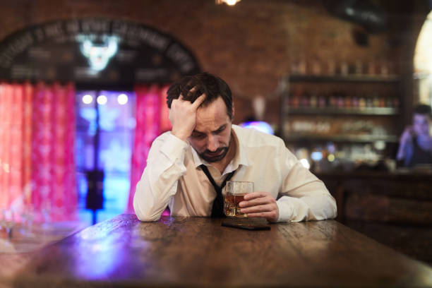 Depressed Man Drinking in Bar Portrait of depressed man drinking alcohol alone in bar, copy space bar drink establishment photos stock pictures, royalty-free photos & images