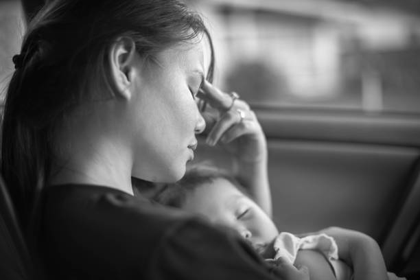 Depressed mother holding her baby, tired and stressed. Postpartum. Tired mom taking a nap with her child. Postpartum depression. struggle stock pictures, royalty-free photos & images