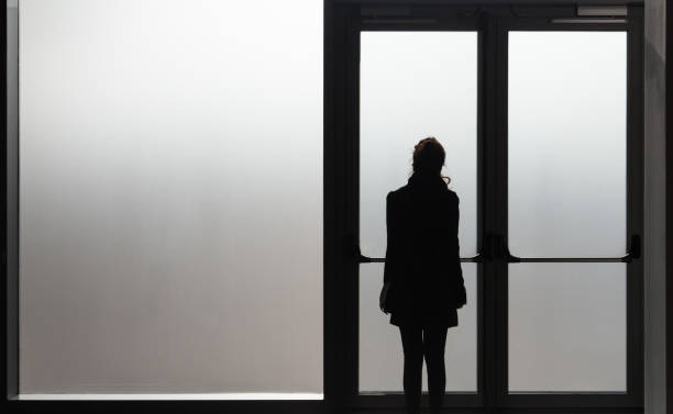 femme déprimée en attente devant une porte en verre dans une salle blanche prête à réagir - maladie - abuse - phobie concept - parent adolescent anxiété photos et images de collection