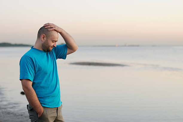 depressão-homem careca em pé junto ao mar - bald beach imagens e fotografias de stock