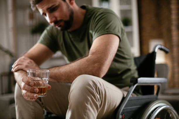 Depression man in wheelchair drinking alcohol at home. stock photo