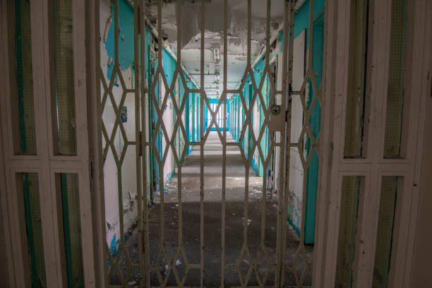 Derelict prison Steel gate across the corridor of prison cell doors inside an abandoned prison. strangford lough stock pictures, royalty-free photos & images