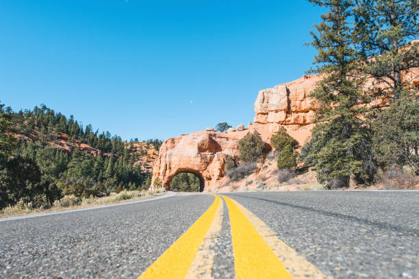 Desert Highway in Bryce Canyon Desert Highway at Bryce Canyon, Utah, USA. The road passes through a natural arch. garfield county utah stock pictures, royalty-free photos & images