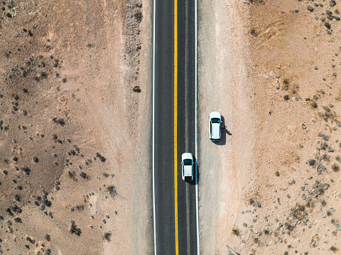 Cars driving on a straight open highway through desert landscape near Las Vegas in Nevada, USA. Seen directly from above.