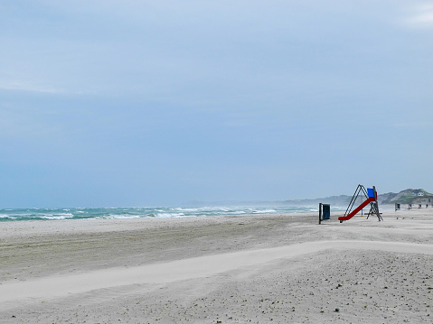 Hvide Sande, Denmark - August 13,2018: Lonely woman on the beach. Hvide Sande in Denmark has 40 km sandy beaches.Hvide Sande is the epitome of beaches, dunes, sun, wind and especially clean air.West Jutland, Denmark.