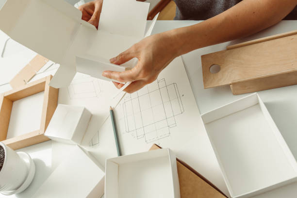 Designer draws a mockup for crafting eco cardboard box. Development a sketch of paper packaging. stock photo