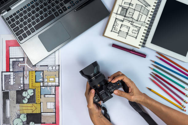 Designer working at office desk with camera, laptop, tablet, illustration stock photo