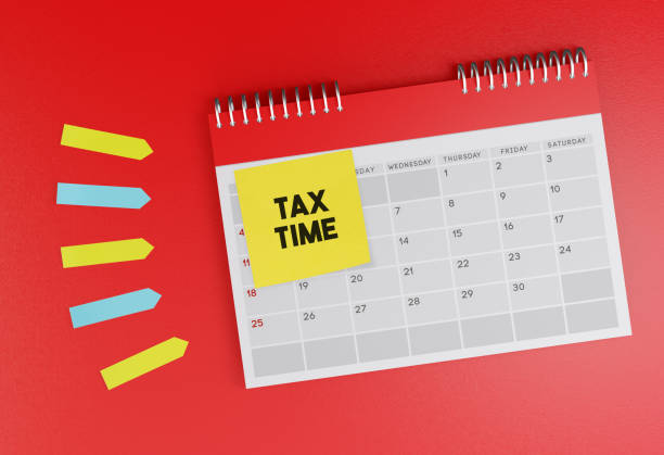 Desk calendar standing on red background. With Tax Time sticky note paper. stock photo