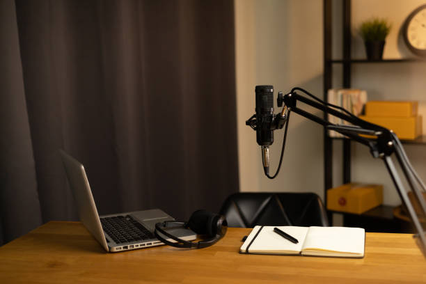 Desk of host streaming radio podcast at home broadcast studio.Such as laptop condenser microphone and headphone on table. Recording host streaming radio podcast interview conversation at home stock photo