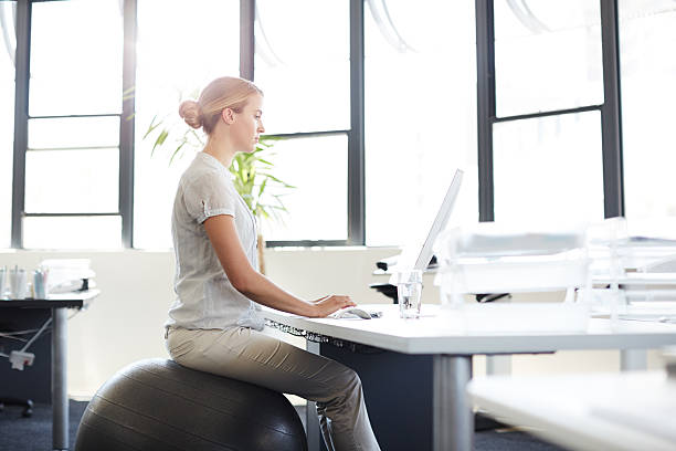 De-stress at your desk Shot of woman sitting on a swiss ball while working at her computer in an officehttp://195.154.178.81/DATA/i_collage/pu/shoots/805874.jpg yoga ball work stock pictures, royalty-free photos & images
