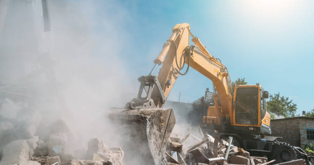 Destruction of old house by excavator. Bucket of excavator breaks concrete structure stock photo