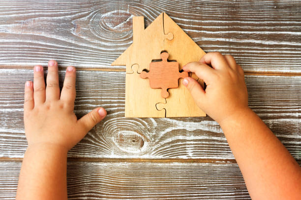 Detail from a wooden house from puzzles in the hands of a child on a wooden background. stock photo