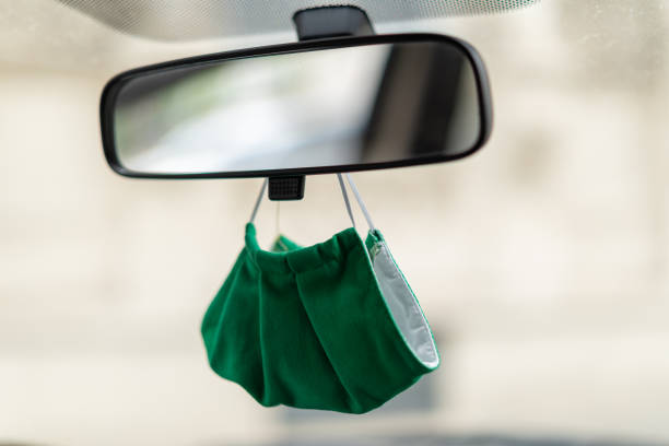 detail mouth nose mask under mirror of taxi car close up green face mouth nose mask hanging under rear-view mirror of car at front wind shield screen in times of covid-19 coronavirus rear view mirror stock pictures, royalty-free photos & images