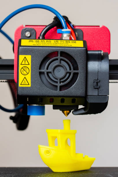 Detail of 3D printer printerhead with hotend and fan. Little plastic FDM ship model. Vertical photo. stock photo