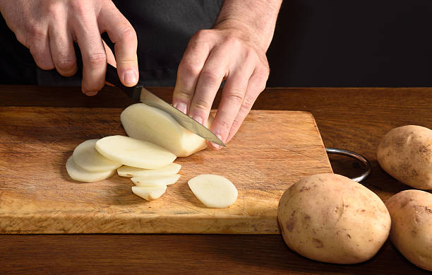 detail of a chef slicing potatoes stock photo