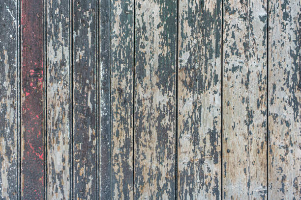 Detail of a wooden wall of a barn made of vertical, weathered boards with peeling green and red paint stock photo