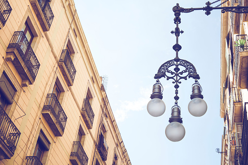 Detail of typical street lamp with facade of old buildings near Sant James (Sant Jaume) Square in Barcelona, Spain, place where City Council of Barcelona and Autonomous Goverment of Catalonia are located.