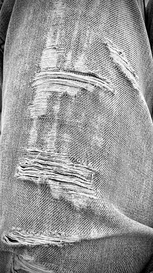 Close up view of worn fabric of a blue jeans.