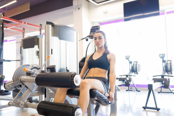 Determined To Lead Healthy Lifestyle Portrait of woman in sportswear sitting on leg curl machine leg curl  stock pictures, royalty-free photos & images