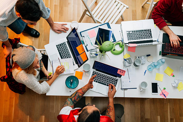 Developers Working In Their Office. Overhead view of young entrepreneurs working in their start-up home office. They are coding on laptops. Create a team stock pictures, royalty-free photos & images