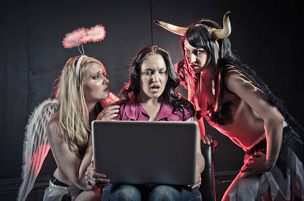 A devil and angel try to persuade a woman using the internet stock photo