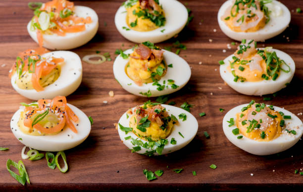 Deviled eggs. Classic American appetizer or picnic favorite. Hard boiled eggs, cut in half, yolk mixed w/ mayonnaise, salt & pepper. Garnished w/ scallions, bacon & paprika. Easter dinner staple. stock photo