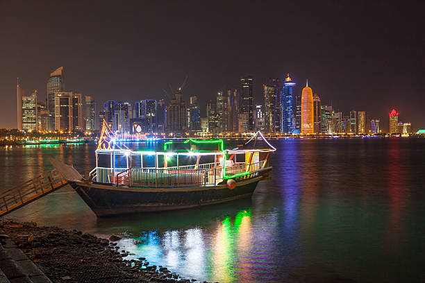 Dhow and Doha skyline at night Cruise dhow and Doha downtown skyline illuminated at night. Qatar, Middle East dhow stock pictures, royalty-free photos & images
