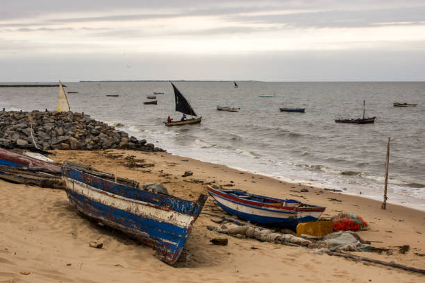 Dhows at Maputo Bay Weaterd dhows on the sandy beach of Maputo, Mozambique, with other boats leaving the small fishing harbor in the early morning maputo city stock pictures, royalty-free photos & images