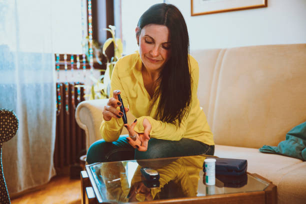Diabetic Woman doing blood glucose measurement in her living room stock photo