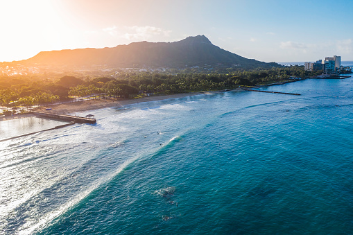 Diamond Head Mountain and Waikiki Queens Beach during sunrise. Palms on the beach with light effect. Oahu Island, Hawaii