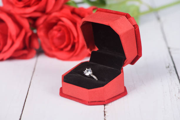 Diamond ring in red jewel box with flower background on wooden table Diamond ring in red jewel box with flower background on wooden table wedding ring box stock pictures, royalty-free photos & images