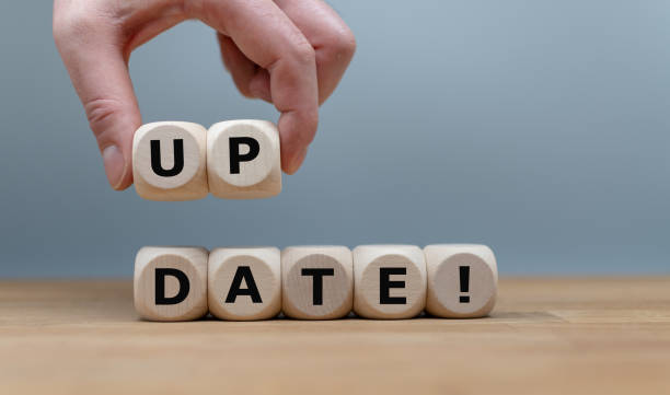 Dice form the word "UPDATE!" while a hand rises the letters "UP". stock photo