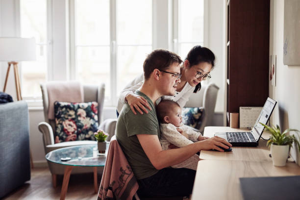 Did you see any diaper specials yet? Shot of a couple looking at something on a laptop while sitting with their baby looking stock pictures, royalty-free photos & images