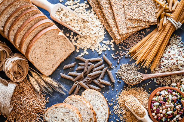 Dietary fiber food still life Top view of wholegrain and cereal composition shot on rustic wooden table. This type of food is rich of fiber and is ideal for dieting. The composition includes wholegrain sliced bread, wholegrain pasta, oat flakes, flax seed, brown rice, mixed beans, wholegrain crackers and spelt. Predominant color is brown. DSRL studio photo taken with Canon EOS 5D Mk II and Canon EF 100mm f/2.8L Macro IS USM whole stock pictures, royalty-free photos & images