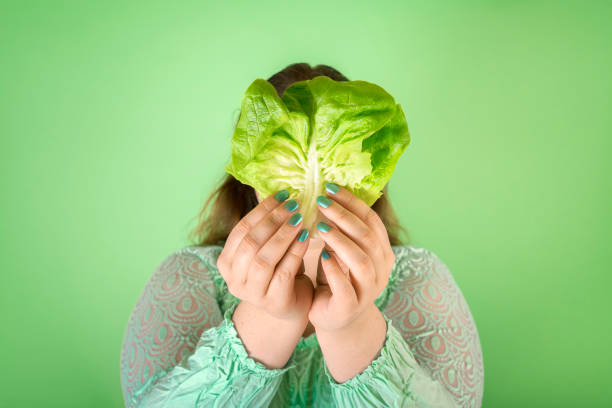 Dieting concept with a chubby woman holding a salad leaf Fat woman holding in hands a salad leaf, dieting with vegetable concept image. Dieting with green food for good health. Detox vegetables aqua menthe photos stock pictures, royalty-free photos & images