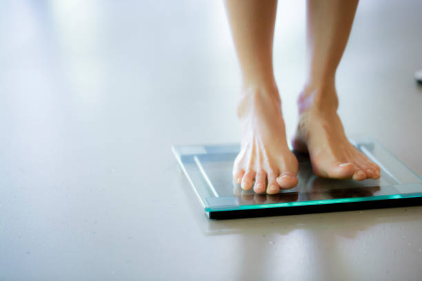 Dieting Female is dieting and checking her weight on the scale, selective focus weight scale stock pictures, royalty-free photos & images