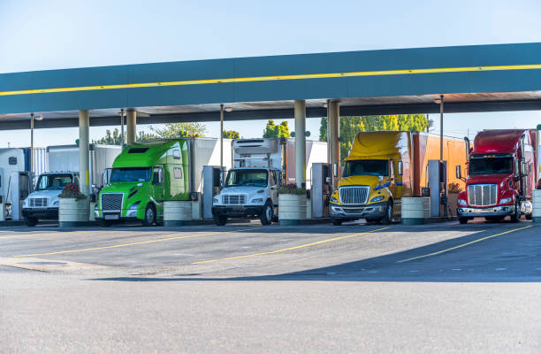 Different big rigs semi trucks standing on fuel station for truck refueling and continuation of the route stock photo