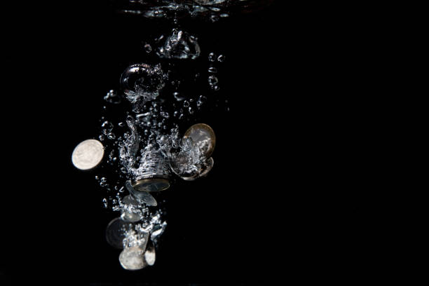 Different coins splashing in water. stock photo