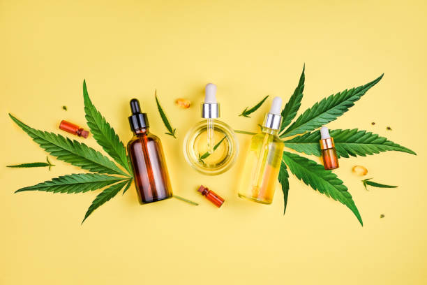Different glass bottles with CBD OIL, THC tincture and cannabis leaves on yellow background. Flat lay, minimalism. Cosmetics CBD oil. Glass bottle and dropper CBD OIL, THC tincture and cannabis leaf on background. Laboratory Production of cosmetics with CBD oil. cbd oil stock pictures, royalty-free photos & images