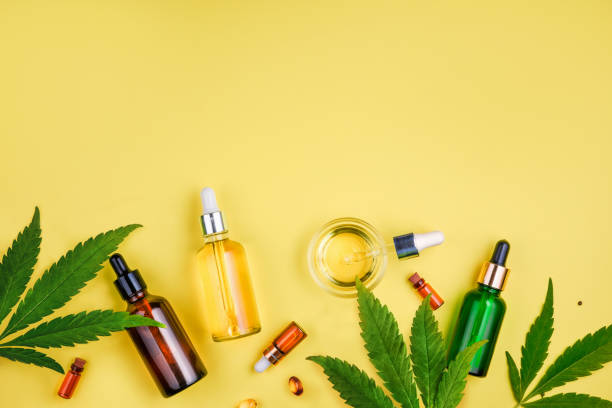 Different glass bottles with CBD OIL, THC tincture and cannabis leaves on yellow background. Flat lay, minimalism. Cosmetics CBD oil. Glass bottle and dropper CBD OIL, THC tincture and cannabis leaf on background. Laboratory Production of cosmetics with CBD oil. marijuana herbal cannabis stock pictures, royalty-free photos & images